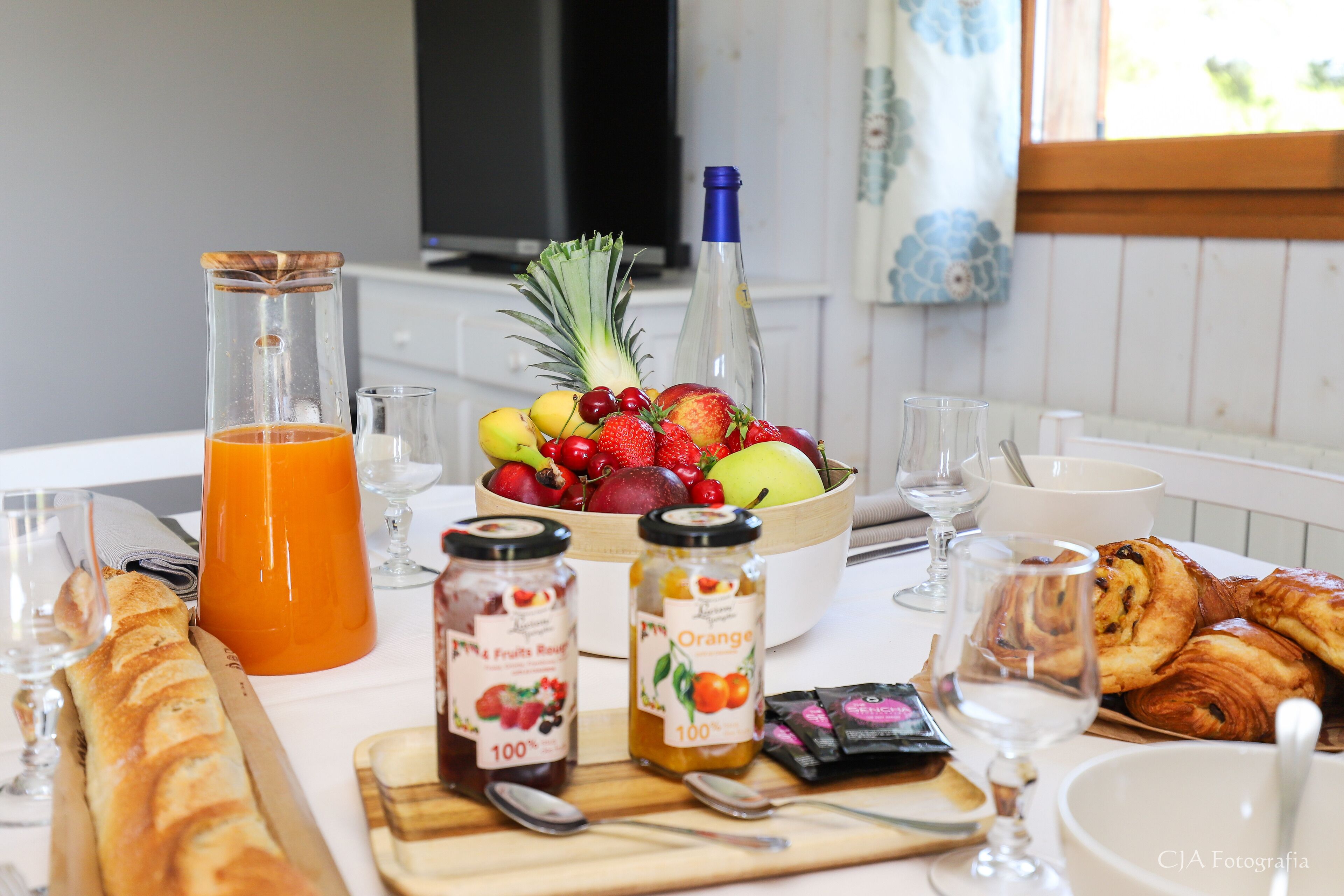 Una mesa de desayuno con una variedad de alimentos, como frutas, pasteles y bebidas.