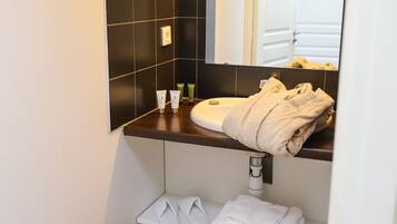 A bathroom with a white sink, black tiles, a mirror, and a towel rack.