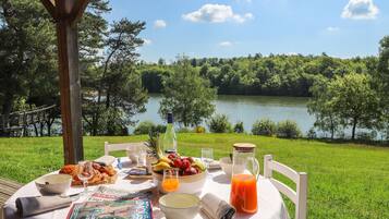 Mesa al aire libre con vistas a un lago, rodeada de vegetación.