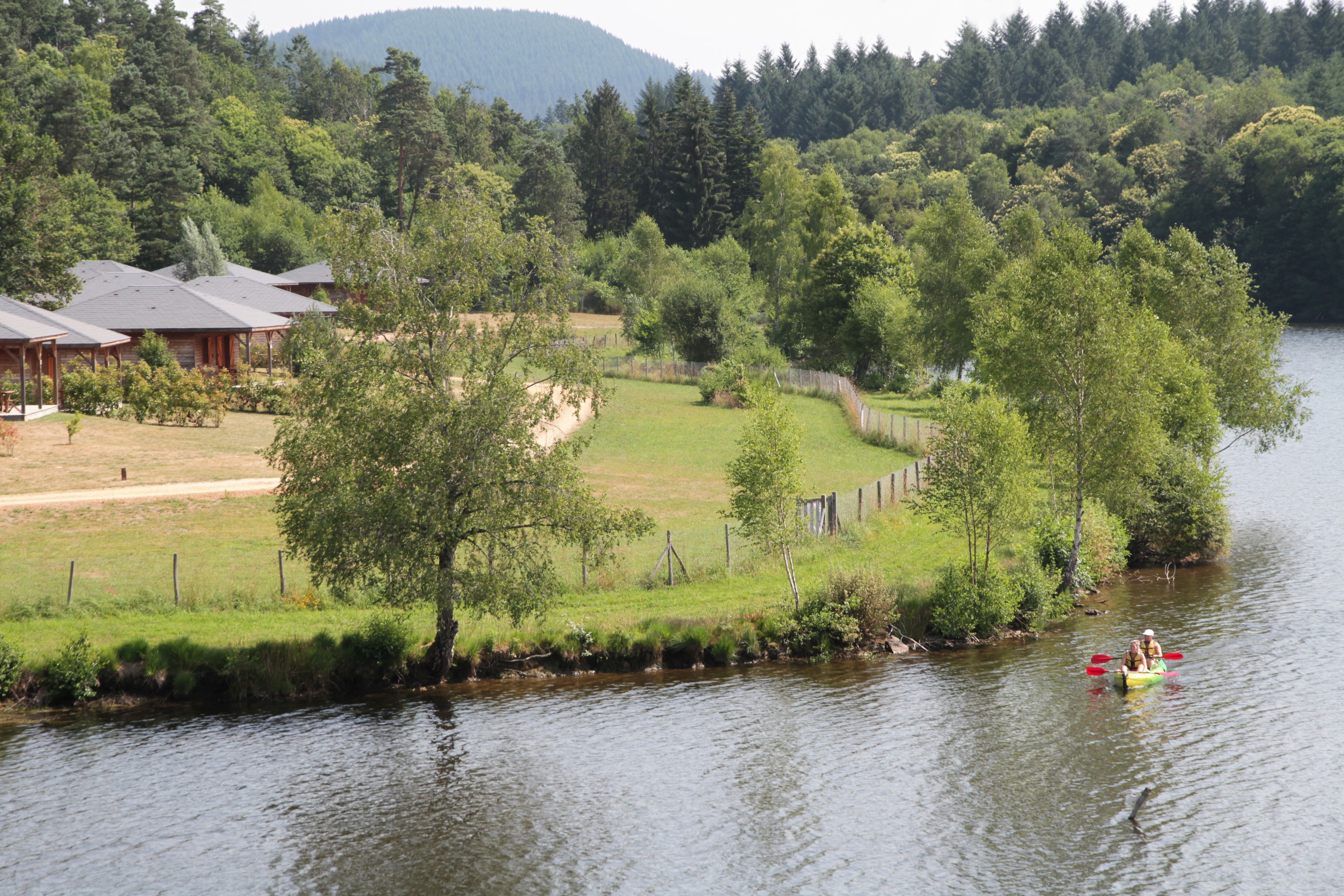A lakeside cabin with a dock, surrounded by lush greenery and a forested backdrop.