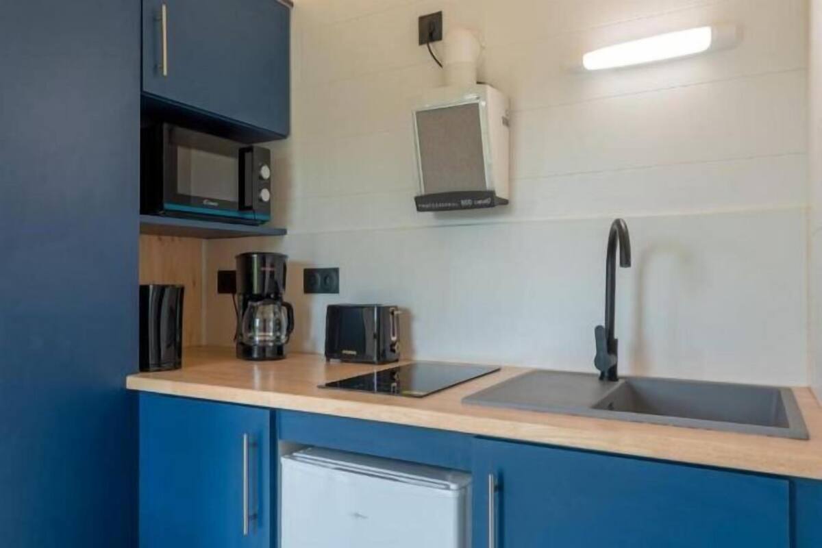 Una cocina compacta con microondas, tostadora, cafetera y lavamanos.