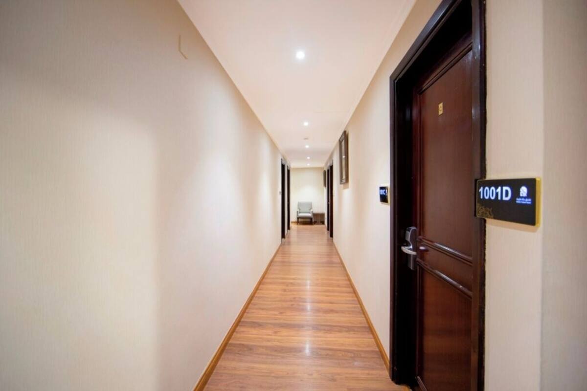 A hotel hallway with wooden flooring, a door labeled "1001D", and a light-colored wall.