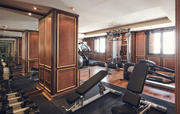 A gym with exercise equipment, a bench press, and a mirrored wall. - Dallah Taibah Hotel (Madinah)
