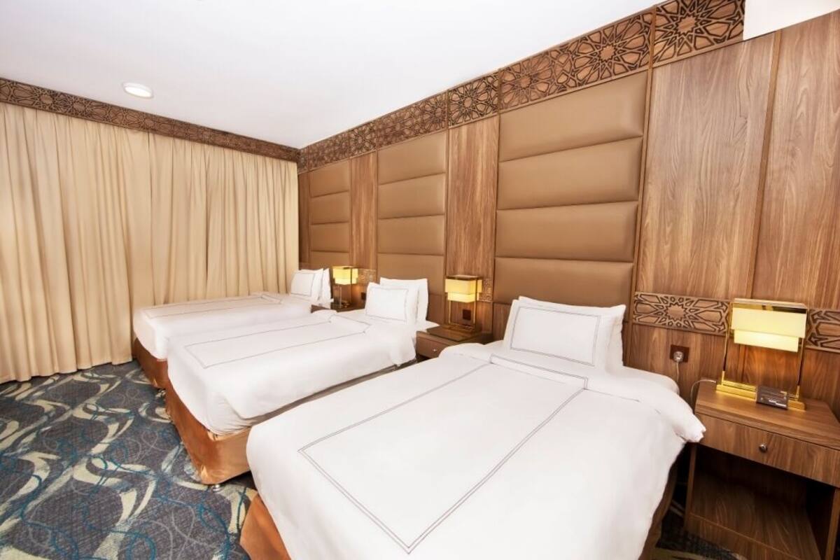 A hotel room with two beds, wooden headboards, and a patterned carpet.
