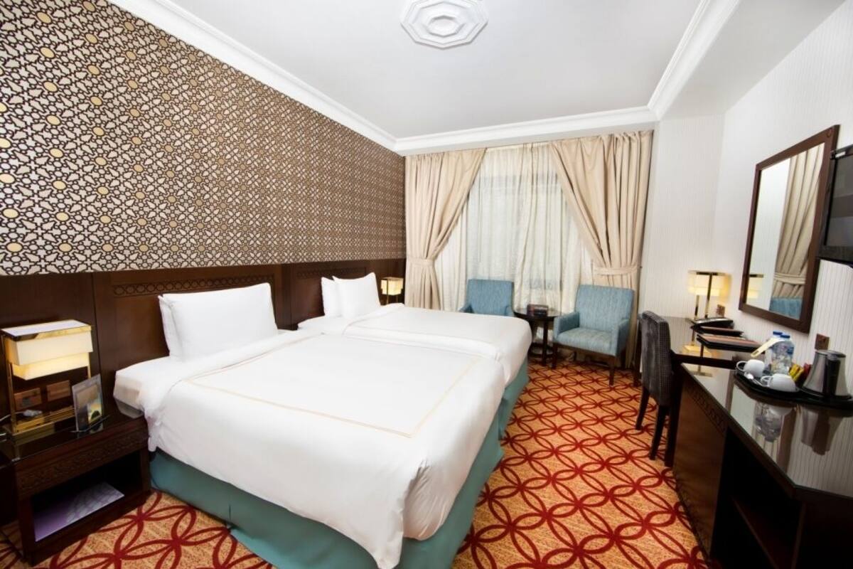 A hotel room with a large bed, a desk, a chair, and a TV.