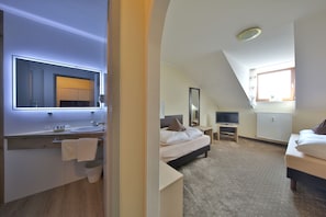 A modern bedroom with a large bed, a bedside table, a TV, and a window. - Hotel Bockmaier (Oberpframmern)