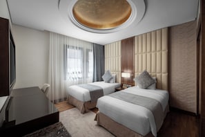 Habitación de hotel con dos camas, un escritorio y un ventanal grande con cortinas.