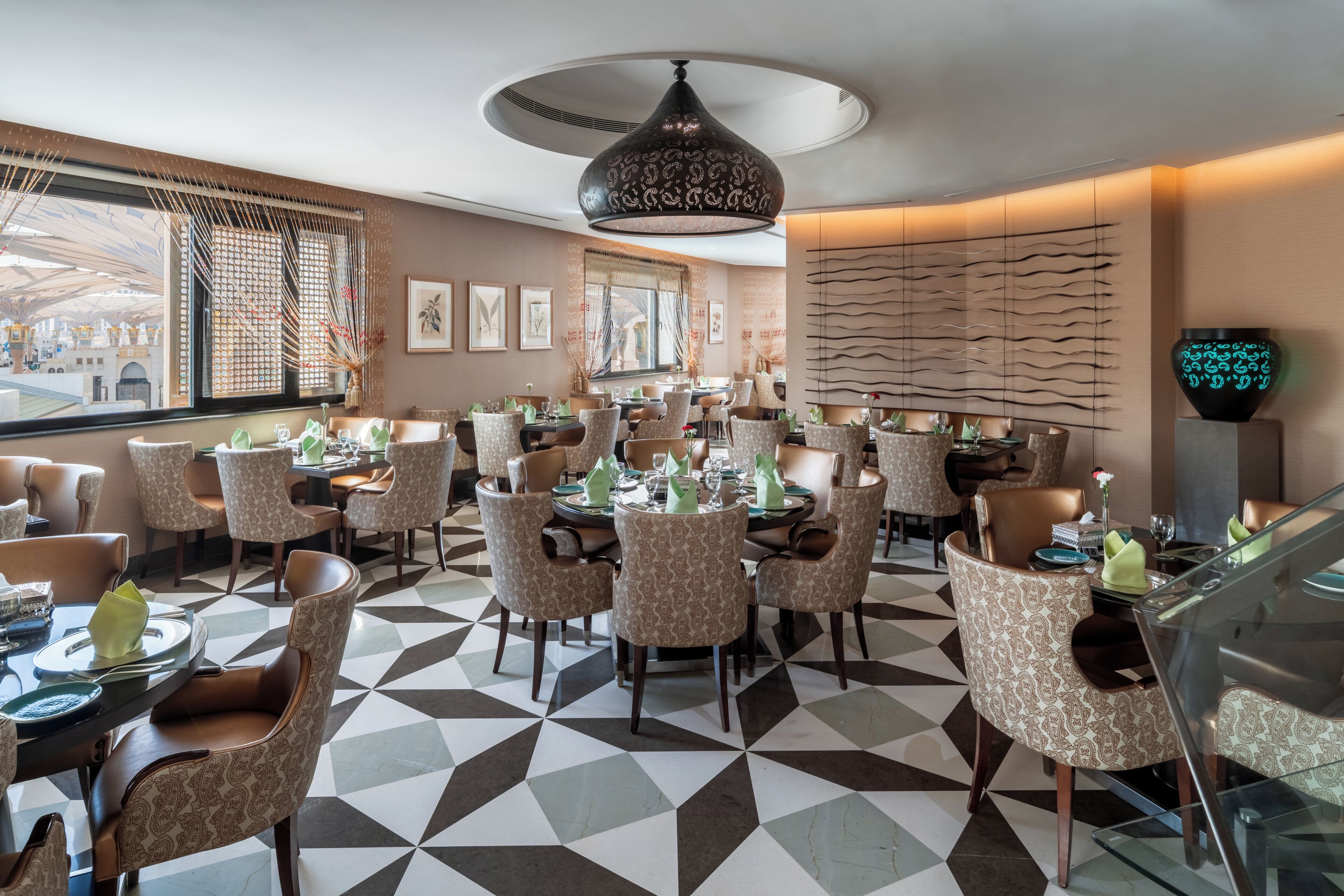A restaurant with a geometric patterned floor, patterned chairs, and a modern pendant light.