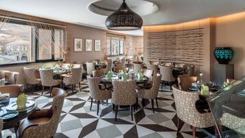 A restaurant with a geometric patterned floor, patterned chairs, and a modern pendant light.