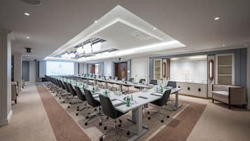 A conference room with a long table, chairs, and a projector screen.