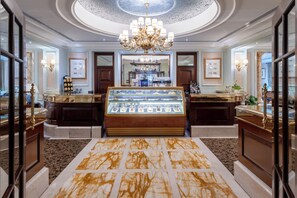 Un hall d’hôtel luxueux, doté d’une vitrine centrale, d’élégants lustres et d’un sol en marbre.