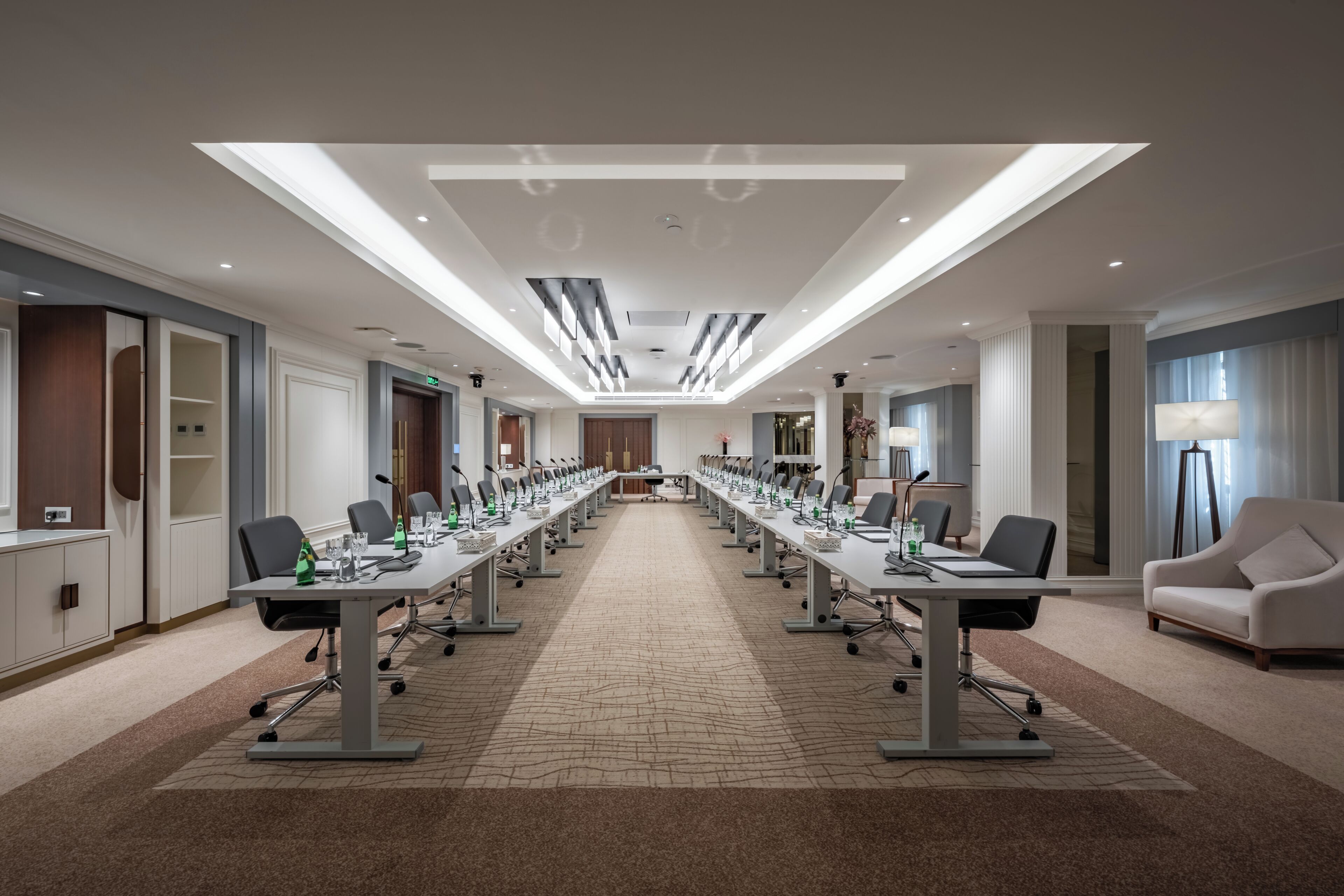 A conference room with a long table, chairs, and a carpeted floor.