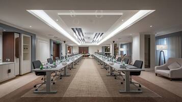 A conference room with a long table, chairs, and a carpeted floor.