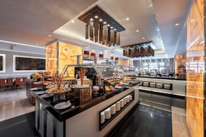 A buffet area with various food items and a seating area with tables and chairs.