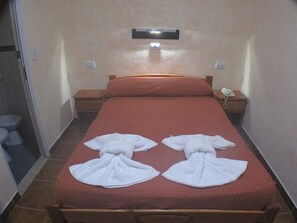 A hotel room with a bed, a bedside table with a phone, and a wall-mounted light fixture. - Los Cedros Hotel (Buenos Aires)