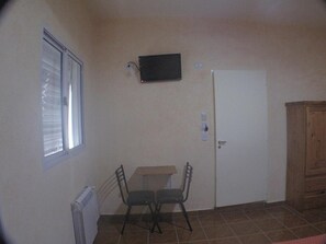 A small room with a white door, a window, a table with two chairs, and a television mounted on the wall. - Los Cedros Hotel (Buenos Aires)