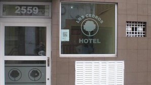Entrada de un hotel con un letrero que dice "Los Cedros Hotel" y el número "2559" sobre la puerta.