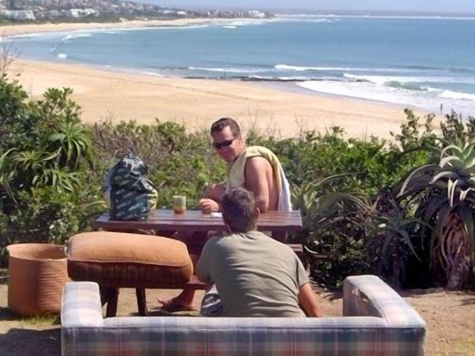 Un comedor junto a la playa con vista al océano, una mesa y sillas.