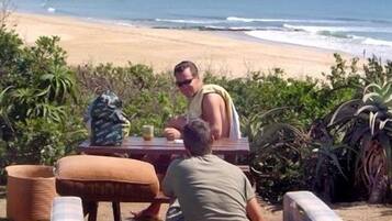 Un comedor junto a la playa con vista al océano, una mesa y sillas.