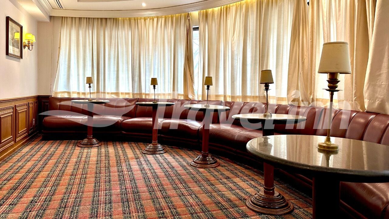 Quarto de hotel com sofá de couro, uma mesa redonda e um tapete estampado.