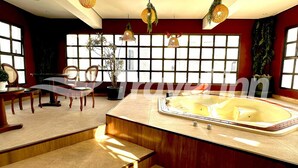 A modern bathroom with a large bathtub, a vanity with a mirror, and a seating area with chairs and a table. - Travel Inn Premium Flats Paulista Wall Street  (São Paulo)