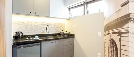 Cocina compacta con armarios grises, lavavajillas y salpicadero de azulejos.