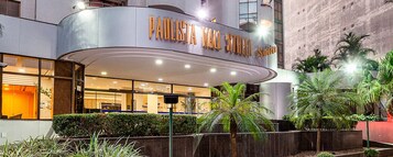 Um edifício moderno com entrada curva e uma placa que diz 'PAULISTA MAIN STREET'.