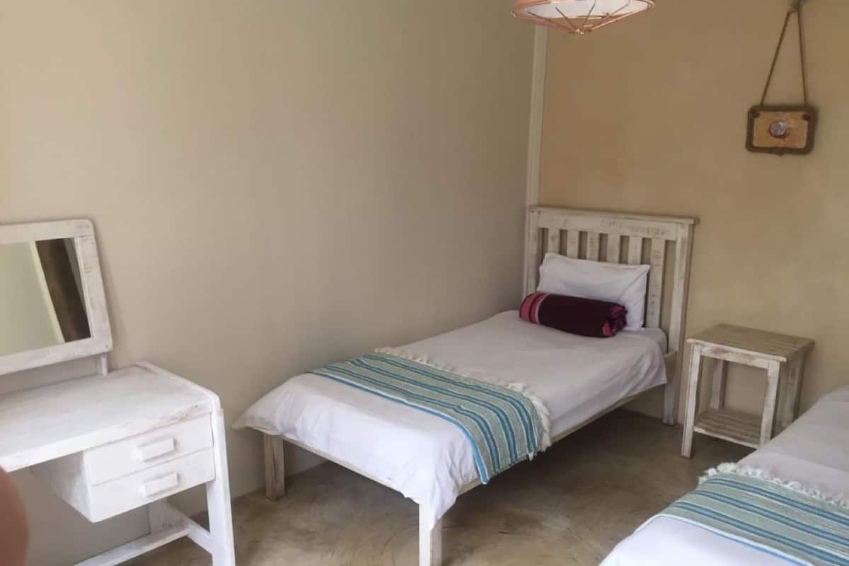 Une petite pièce simple, avec un lit, un bureau et une petite table.