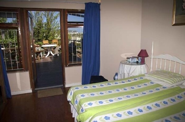 Un dormitorio con cama, mesita de noche, lámpara y vistas a un espacio exterior con mesa y sillas.
