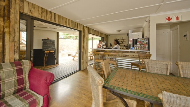A cozy breakfast area with a wooden interior, a chalkboard menu, and a bar counter. - Island Vibe Knysna Hostel (Knysna)