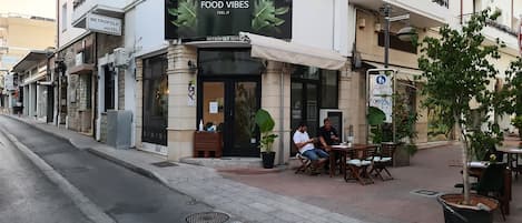 Un restaurante llamado 'Food Vibes' con terraza y un cartel que anuncia el 'Metropole Hotel' contiguo.