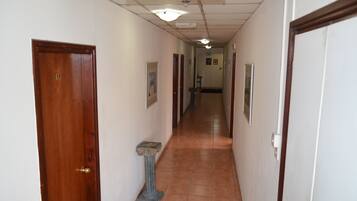 A hallway with wooden doors, a tiled floor, and a small column.