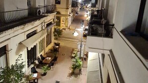 A narrow street with buildings on either side, outdoor seating areas, and a few parked cars. - Metropole Hotel (Limassol)
