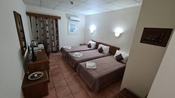Habitación de hotel con dos camas, un escritorio, una silla, un espejo y una ventana con cortinas.