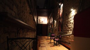 A narrow corridor with stone walls, a tiled floor, and several chairs. - Metropole Hotel (Limassol)