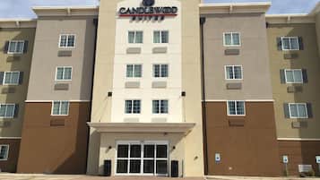 A multi-story hotel with a central entrance, air conditioning units on each floor, and a parking lot with handicapped parking signs.