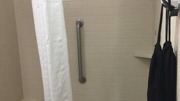 Un baño con bañera, ducha y barra de apoyo.