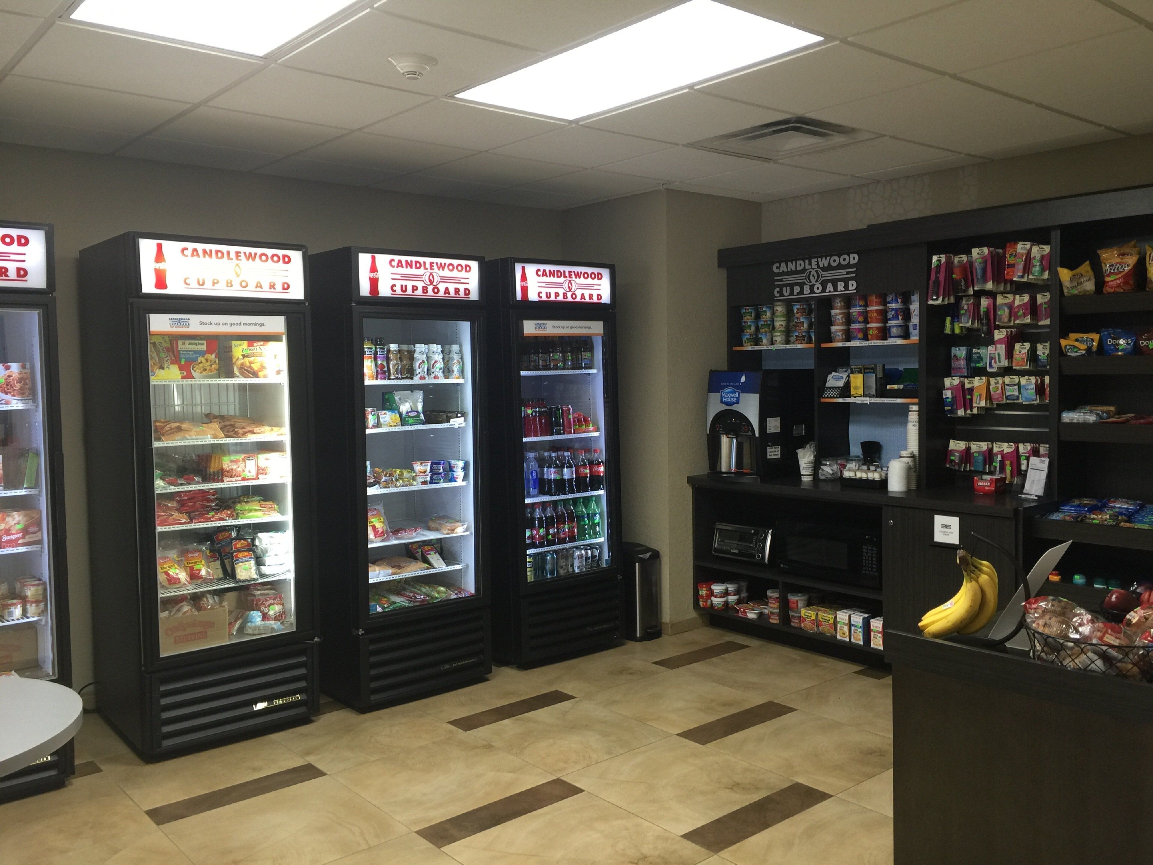 A grocery store with refrigerated sections labeled 'CANDLEWOOD CUPBOARD' and shelves stocked with various products.