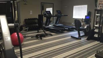 A hotel fitness center with treadmills, weight machines, and a red exercise ball.