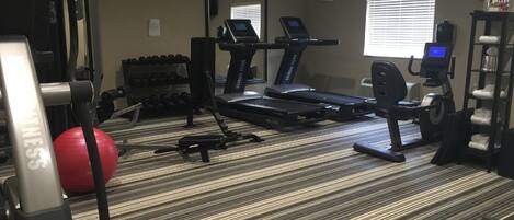 A hotel fitness center with treadmills, weight machines, and a red exercise ball.