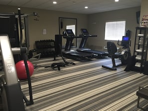 Een hotel fitnessruimte met loopbanden, gewichtstoestellen en een rode fitnessbal.