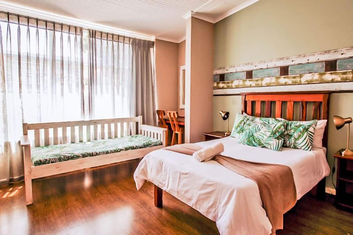 A bedroom with a bed, a wooden bench, a desk, and a chair.