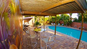 A covered outdoor area with a pool, metal chairs, and a table. - The Russel Guesthouse (Gqeberha (Port Elizabeth))