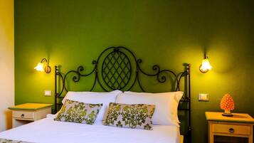 A bed with a green headboard, two bedside tables, and two wall-mounted lamps.