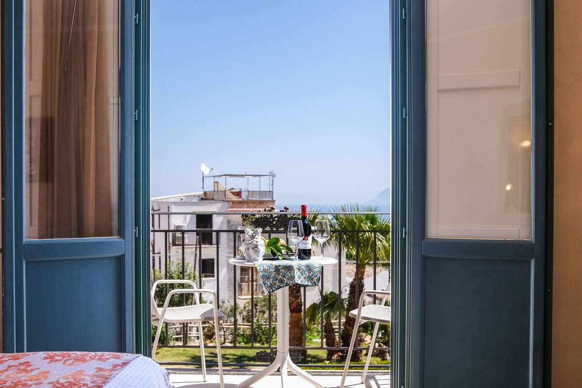 A balcony with a table, chairs, and a view of the sea.
