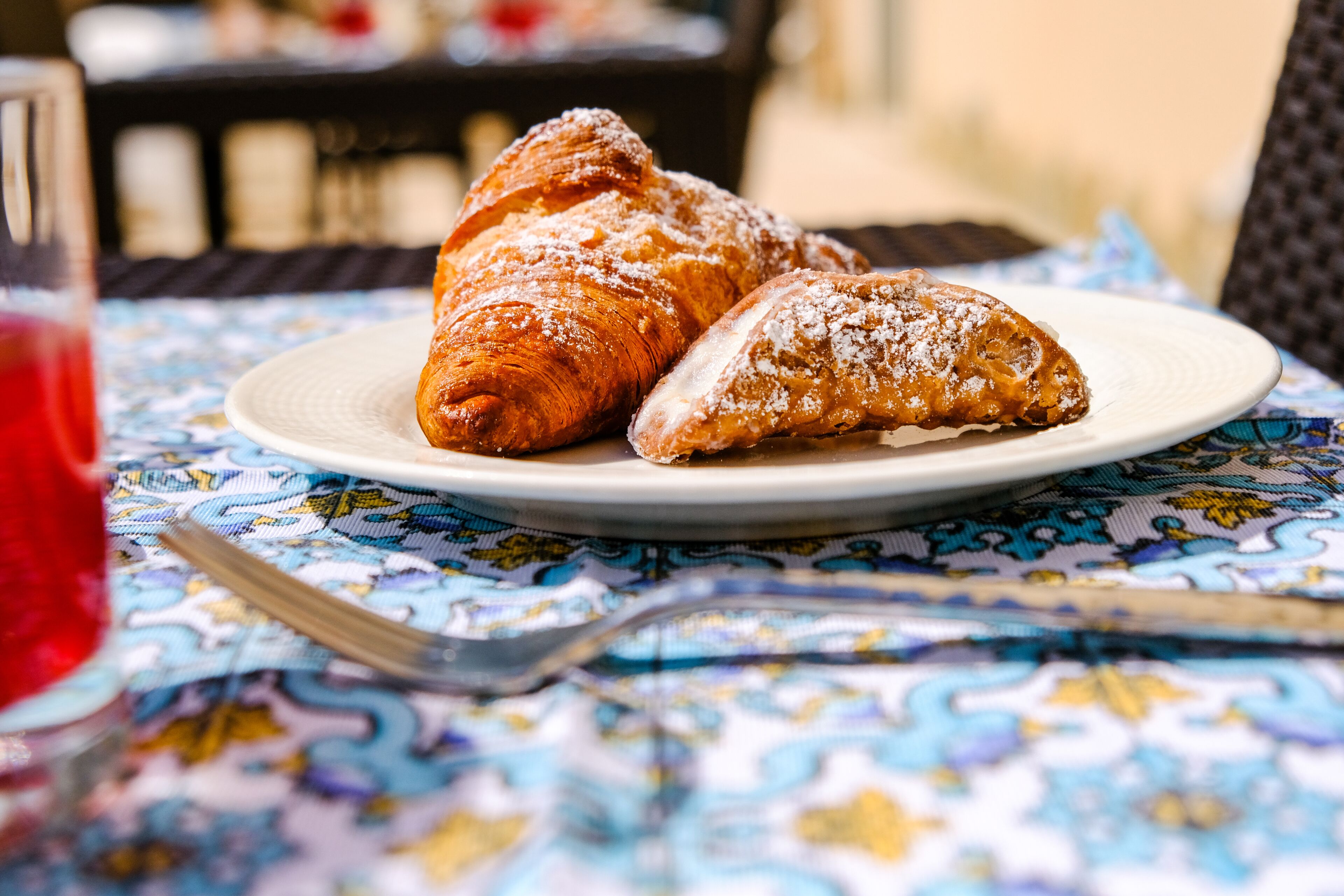 Une assiette avec deux pâtisseries, posée sur une table recouverte d’une nappe à motifs.