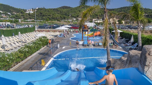 Een waterpark met een groot zwembad, glijbanen en ligbedden.