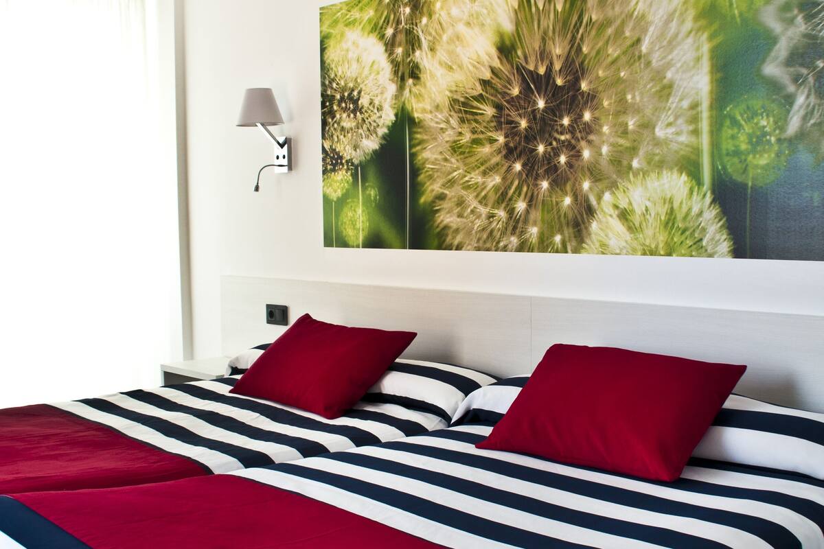 Ein Hotelzimmer mit einem großen Bett, gestreifter Bettwäsche und einer Wandlampe.