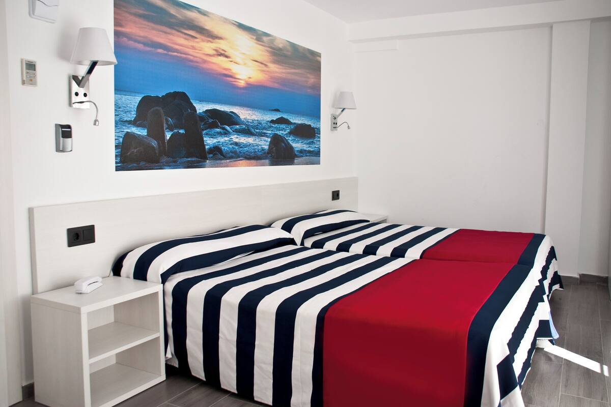 Ein Hotelzimmer mit einem Bett, einem Nachttisch und einer Wandleuchte.