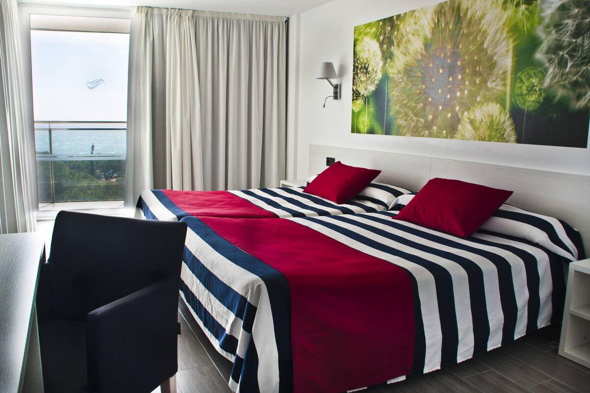 Ein Hotelzimmer mit einem großen Bett, einem Schreibtisch und Meerblick.